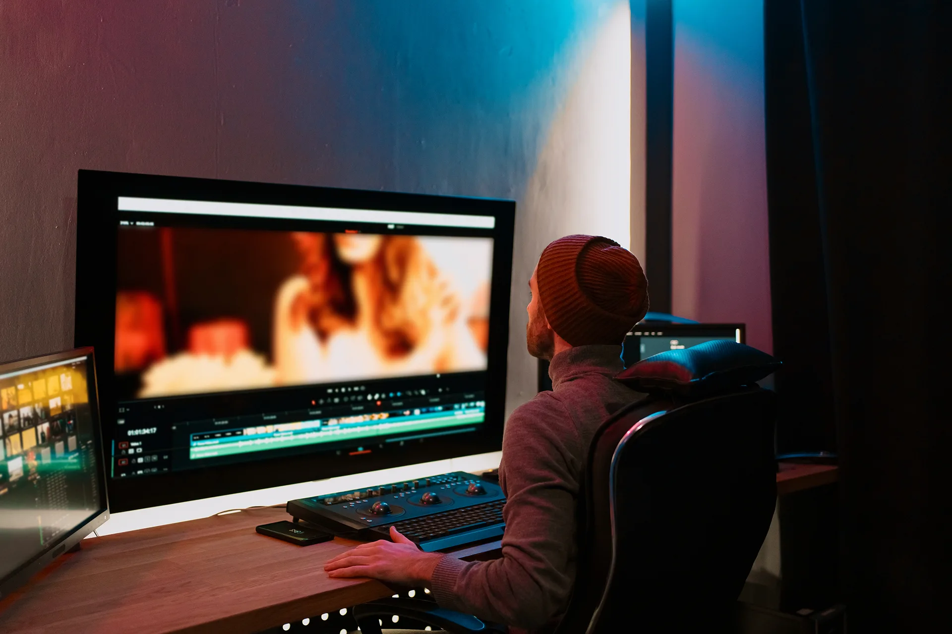 Colorist at a grading suite reviewing footage on a large reference monitor